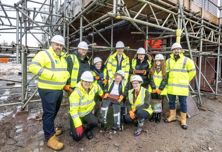 Daisy and her family lay a brick at their home in Gorse Ride. Also pictured is: Barry Williams, project director at Wates Residential (back row centre); Cllr Stephen Conway, leader of the council and executive member for housing (back row right) and Katie Meakin, head of development ? commercial property (back row left). Pic: Stewart Turkington.