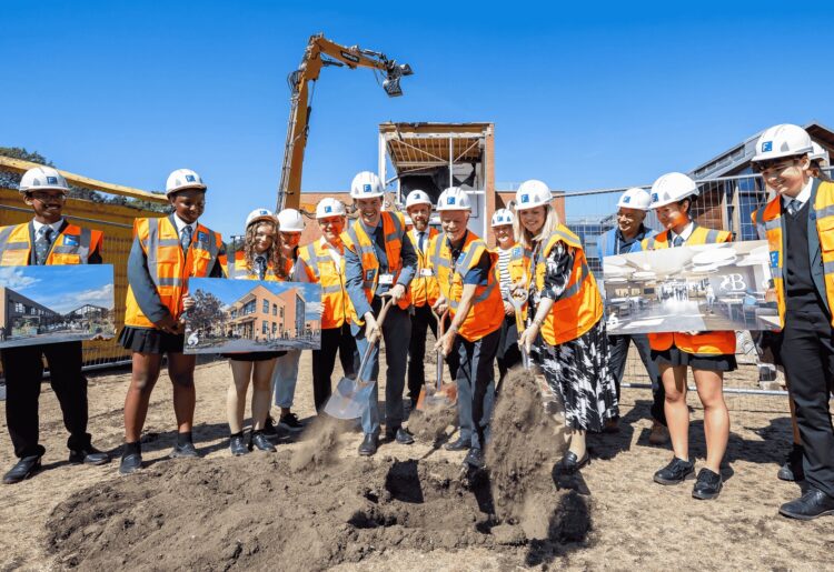 Deputy borough mayor, Cllr Rob Comber, headteacher Jen Comber, and executive headteacher Mark Marande break ground. Also in attendance are representatives from the council and the project?s contractor.