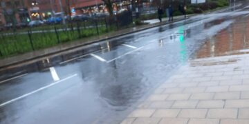 Flooding beside Wokingham's Carnival Pool has forced some pedestrians to jump out of the way to avoid being splashed by passing cars
