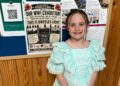 Autumn Turner, a Year 3 pupil at Newbold School, stands beside a poster for the school?s WW1 community exhibition. Picture: Newbold School